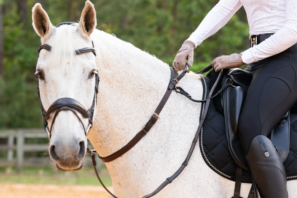 A full view of the brown Correct Connect Double Neck Strap in use on a white horse with rider