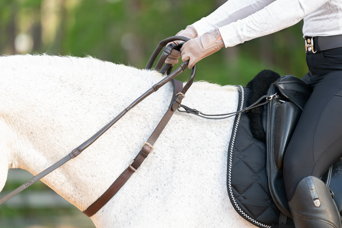 Side view of the Correct Connect Double Neck Strap in use on horse with rider showing how it can attach to saddle