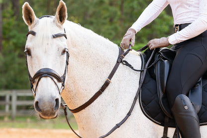 A full view of the brown Correct Connect Double Neck Strap in use on a white horse with rider