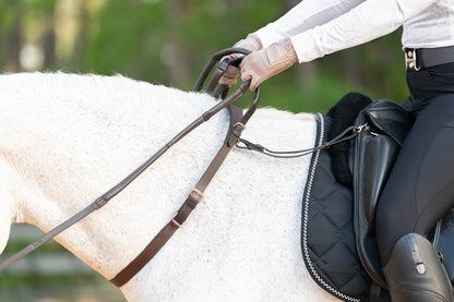 Side view of the Correct Connect Double Neck Strap in use on horse with rider showing how it can attach to saddle